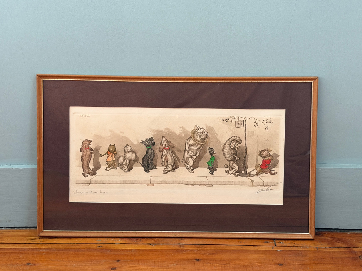 Framed illustration of cartoon dog characters on a wooden surface with a light blue wall background