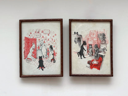 Two framed vintage-style art prints with dark brown textured frames, featuring whimsical black, white, and red illustrations of cats in an interior setting, displayed side-by-side against a plain white wall.　Louis Wain