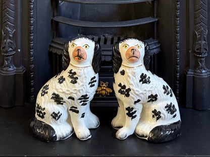 Rare pair of black and white antique Staffordshire Disraeli spaniel dogs, circa 1880, displayed on a Victorian fireplace.